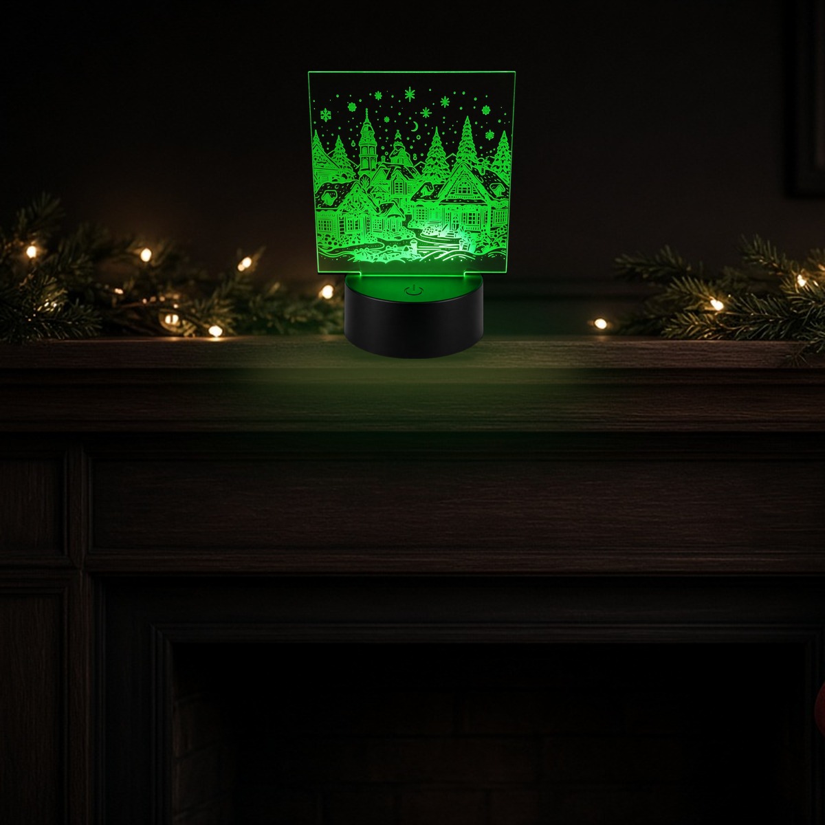 Christmas village laser-engraved acrylic night light, lit in green on a fireplace mantel decorated with string lights